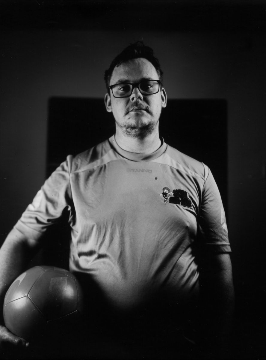 Black and white portrait of a man holding a football