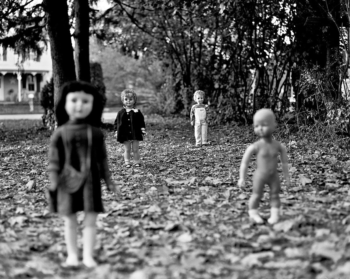 Friday Favourites #spookyfilm. Black and white shot of haunted dolls stood up outside on leaves.