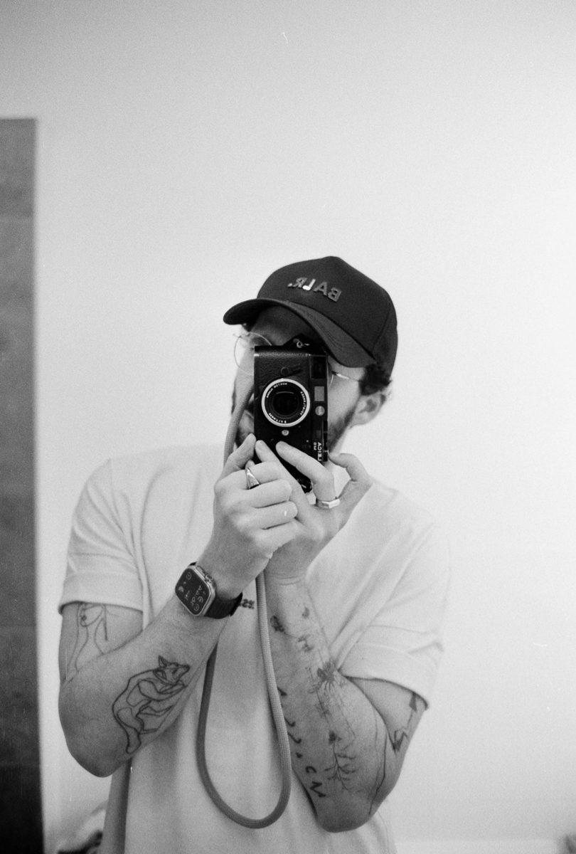 Michèl Passin. Black and white self portrait of a man taking the shot through a mirror.