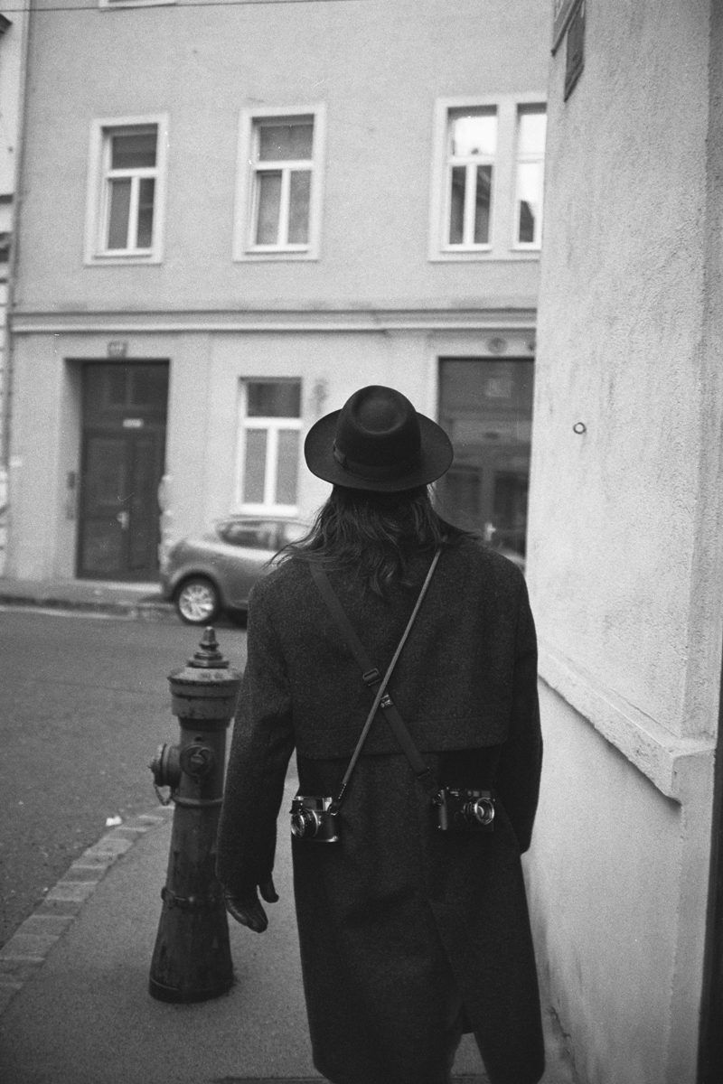 Michèl Passin. Black and white image of a person from the behind walking away on a street.