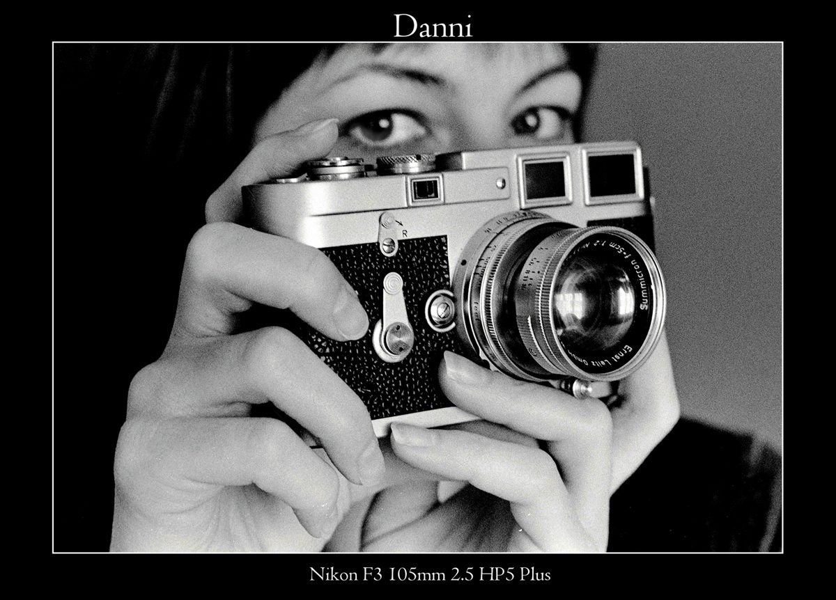 Crombie McNeill. Black and white image of a woman holding a vintage camera to her face.