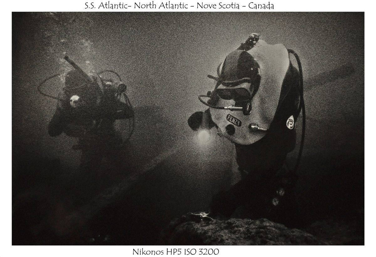 Crombie McNeill. Black and white image of divers deep under water.