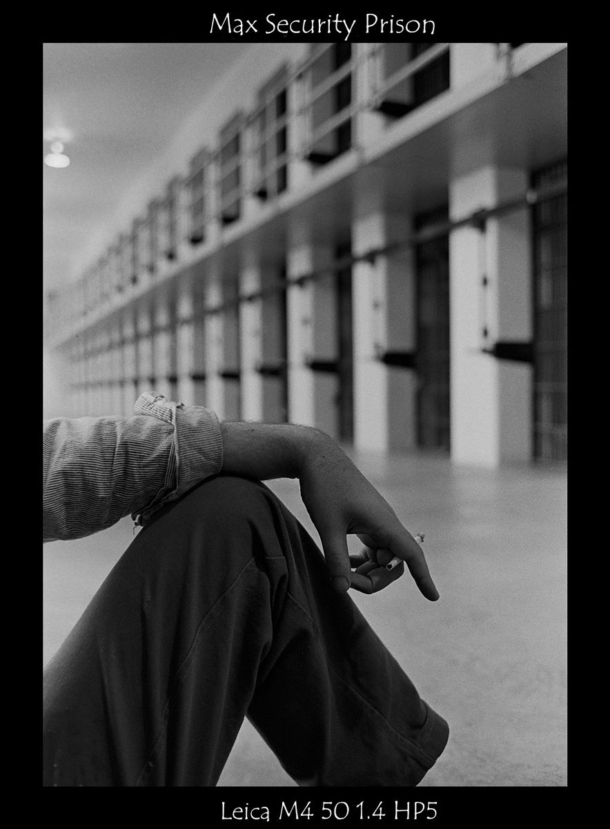 Crombie McNeill. Black and white shot of a persons sat down in prison.