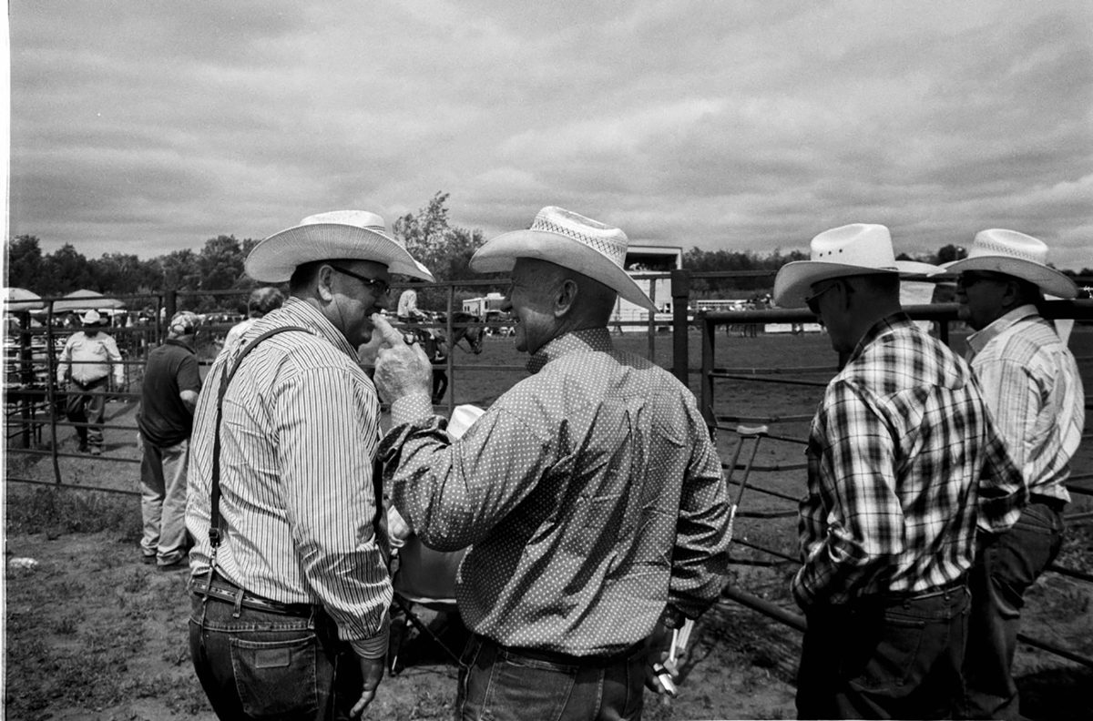 Larry Niehues. Black and white shot of cowboys chatting.