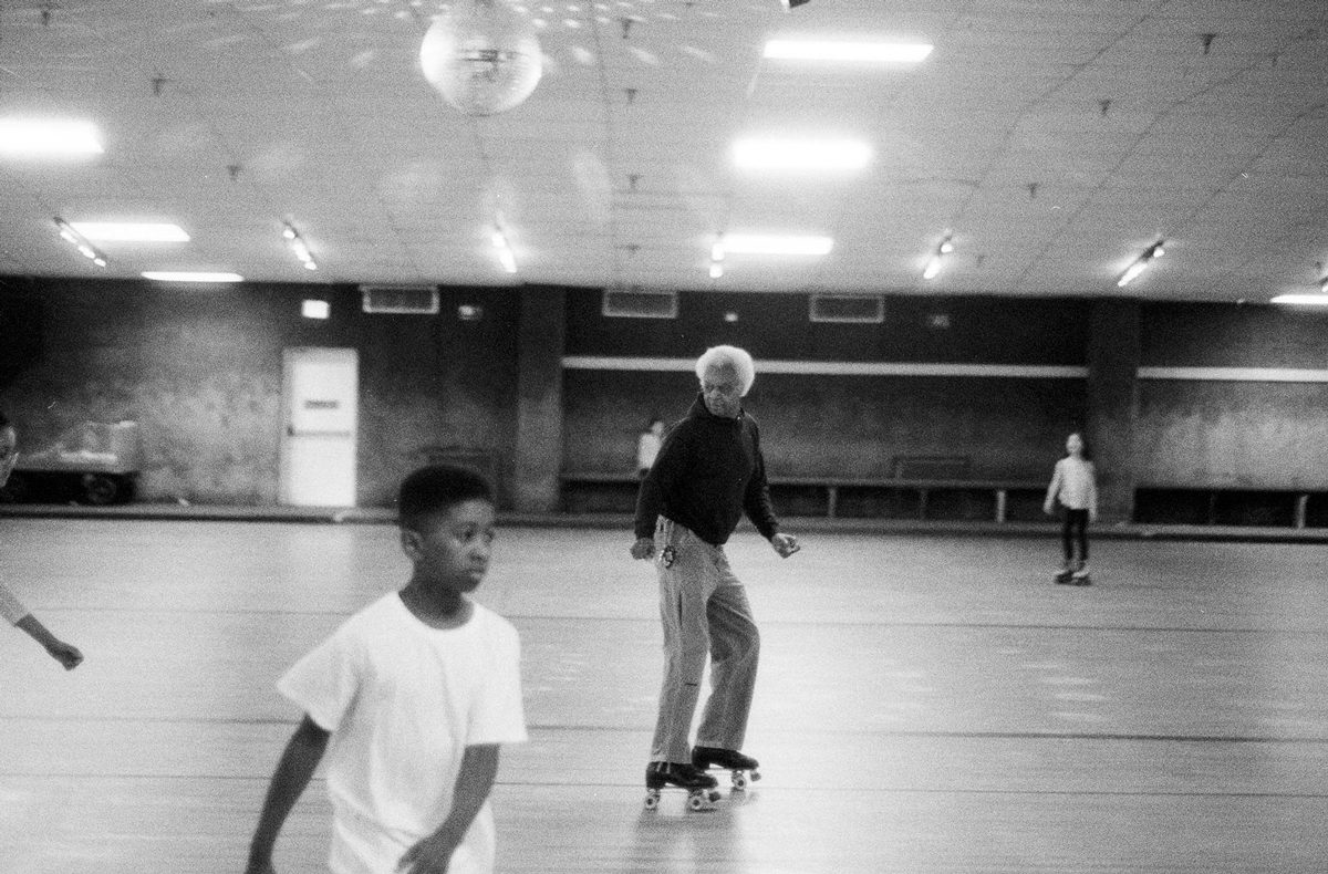 Larry Niehues. Black and white shot of people rollerskating on a roller rink.