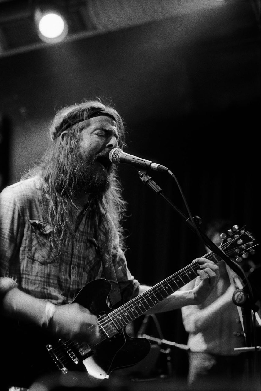 Friday Favourites. Black and white portrait of a man with a beard singing and playing the guitar.