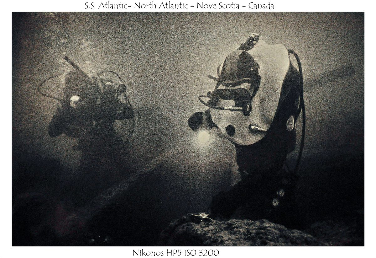 Crombie McNeill. Black and white image of divers deep under water.