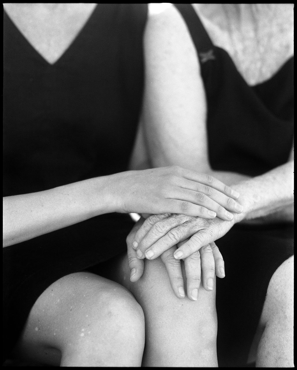 Clarissa Sofia. Black and white image of two women sat down holding hands.