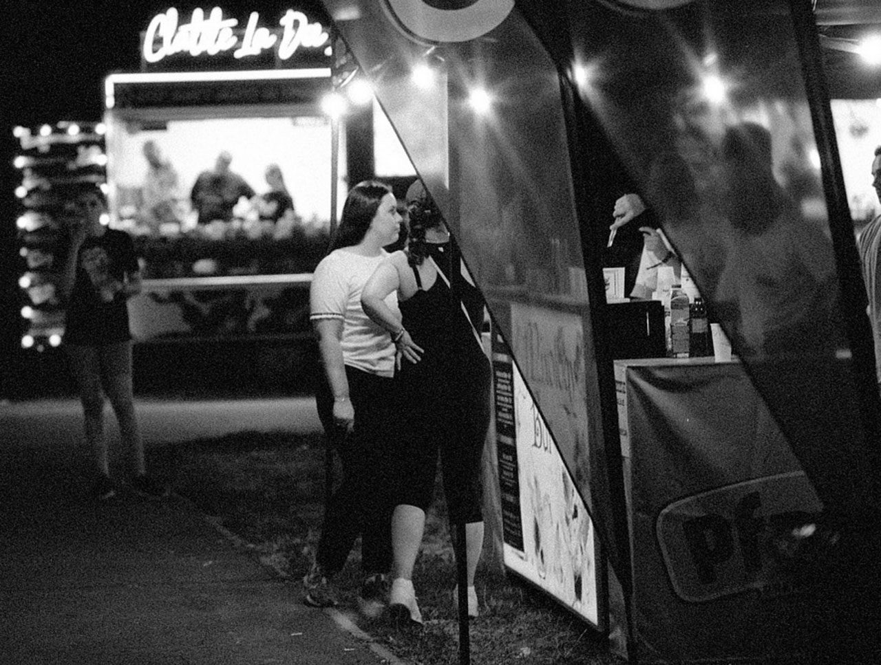 Julian Tanase. Black and white shot of two girls buysing take out food from a truck