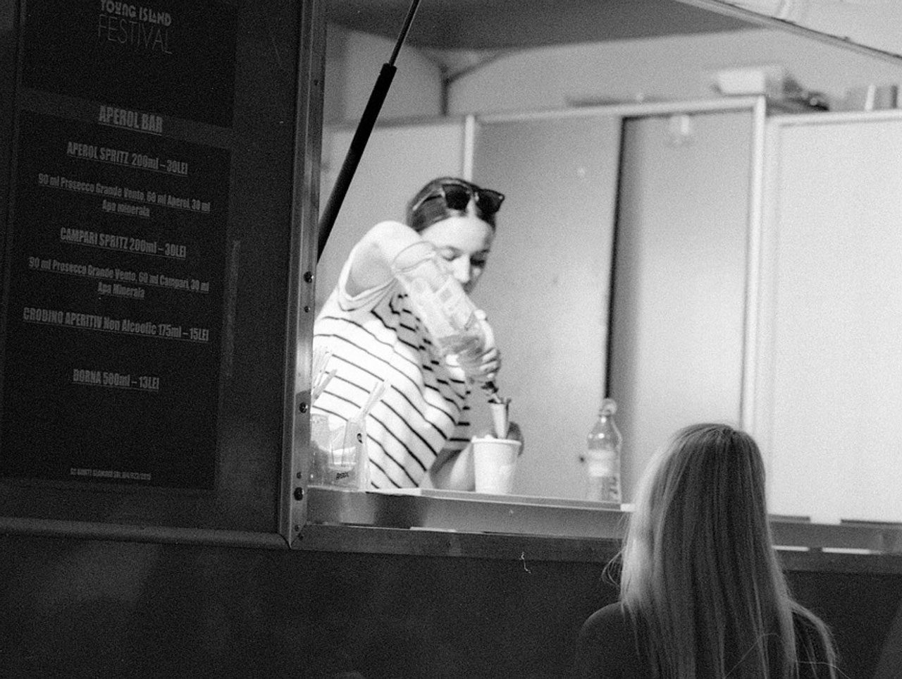 Julian Tanase. Black and white shot of a someone making a coffee and serving in a truck