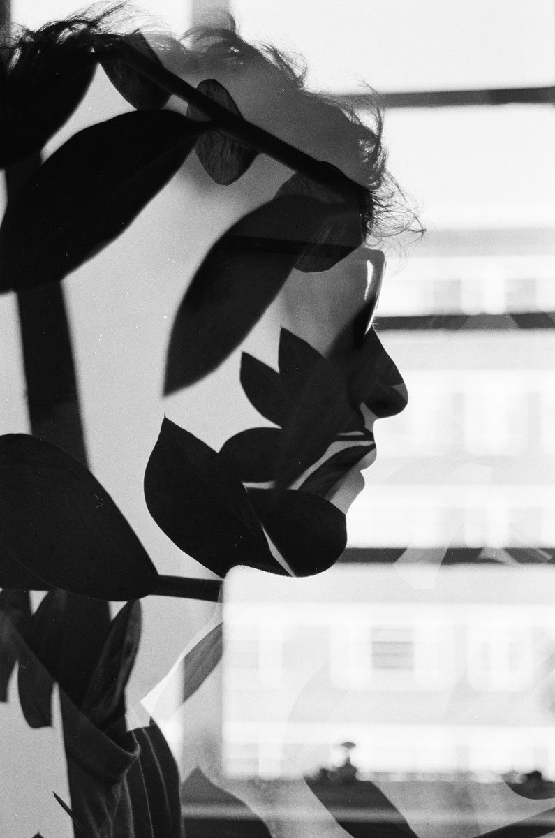 Euan Grimley. Black and white double exposure portrait with plants in the middle.