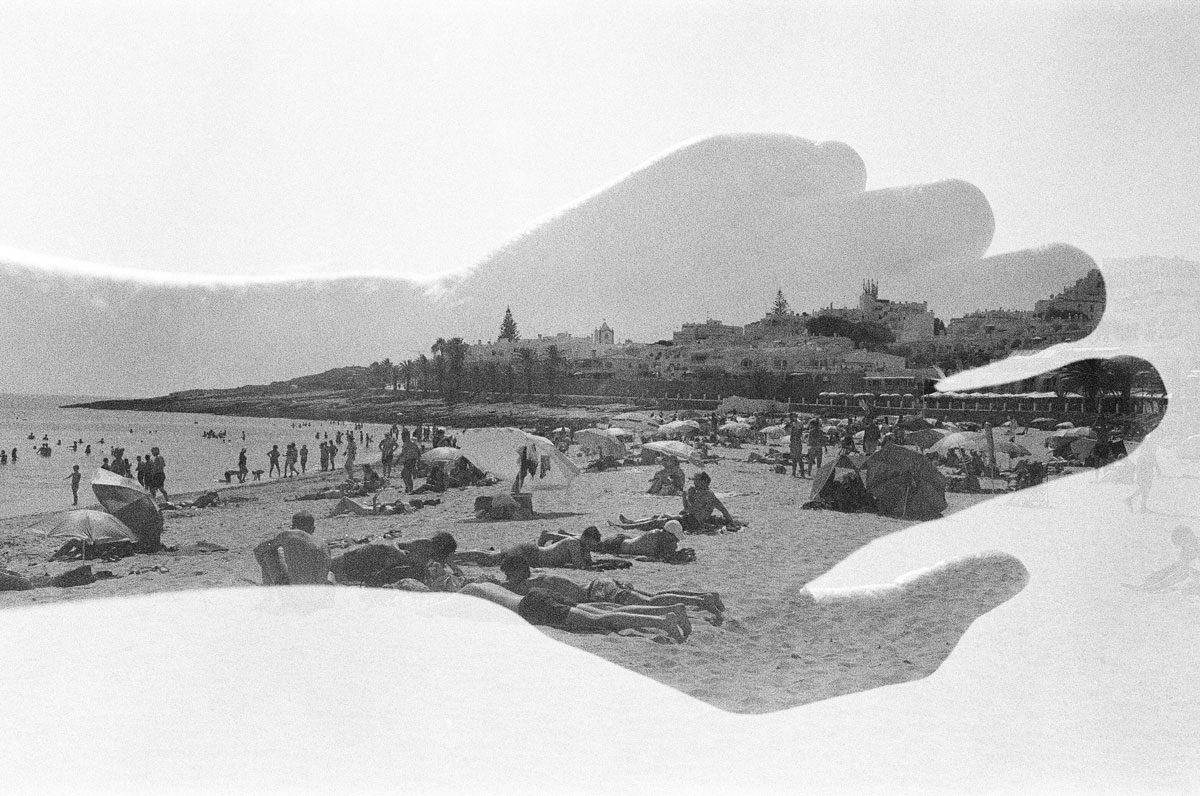 Euan Grimley. Black and white double exposure of a hand landscape with a beach image in the middle.