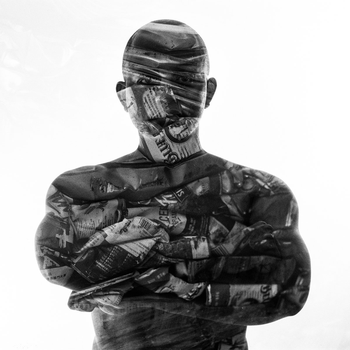 Ben Felton. Black and white double exposure of a man crossing his hands exposed with newspaper.