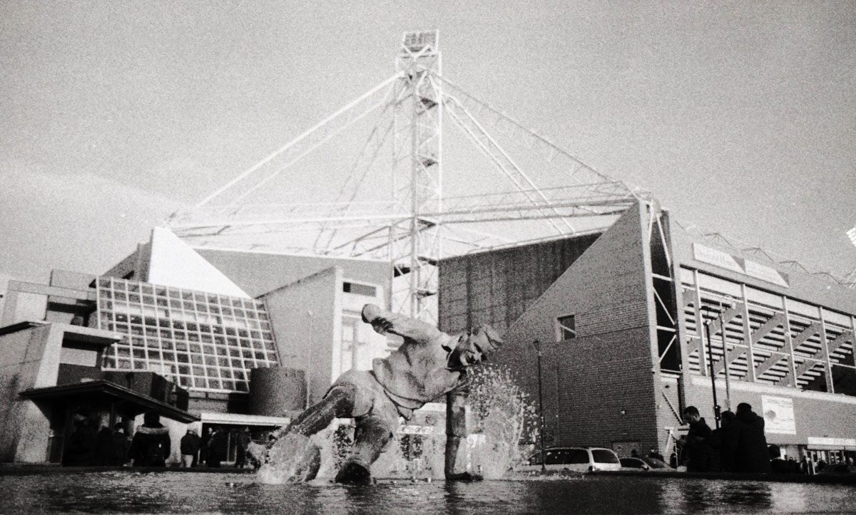 Behind The Film - Kieran Collings. Black and white sepia shot of a football stadium.