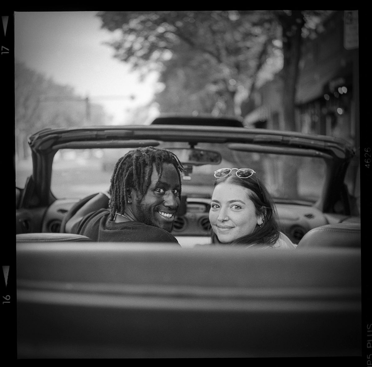 Kenneth Wadja. Black and white portrait of a couple smiling in a car.