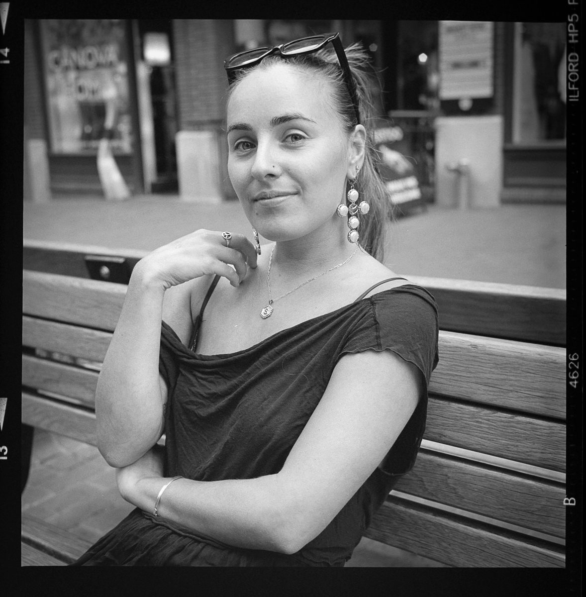 Kenneth Wadja. Black and white portrait of a woman sat on a bench.