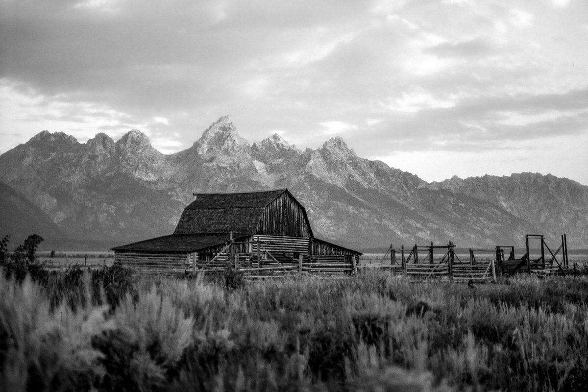 Black and white picture of a cabin with mountains behind